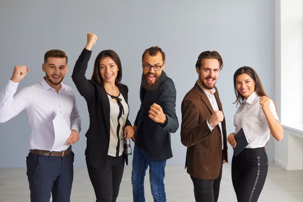 Grupo multicultural de profissionais de negócios expressando alegria e sucesso com punhos cerrados.