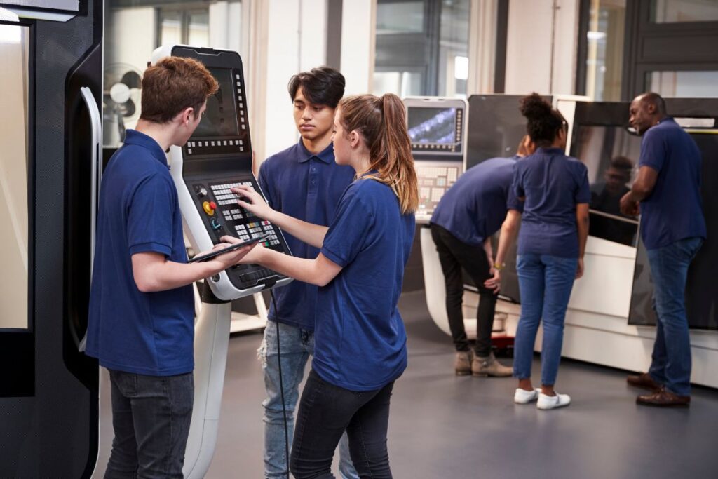 Grupo diversificado de jovens aprendizes aprendendo a operar máquinas industriais com a supervisão de um mentor experiente.