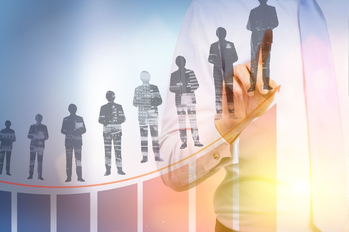 Mão apontando para cima em um gráfico de crescimento com silhuetas de pessoas subindo degraus.