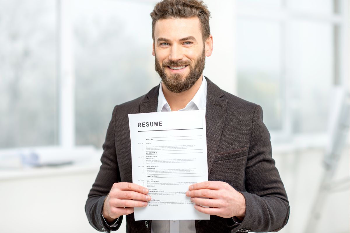 Homem profissional sorridente de terno segurando currículo em escritório moderno